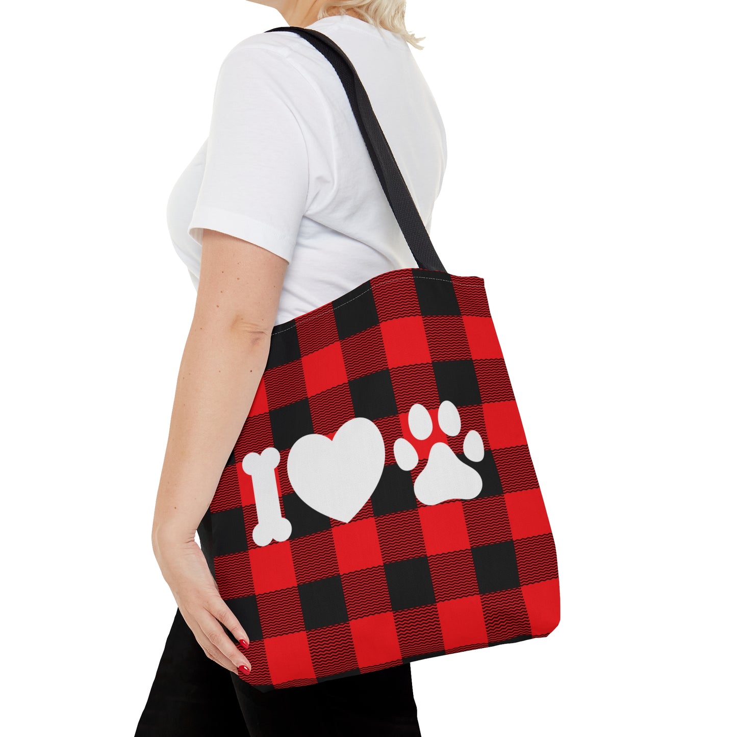 Woman with short blonde hair walking with Buffalo Plaid Tote Bag with white font of I heart dog, the I is a dog bone, followed my heart symbol and then a dog paw print. 