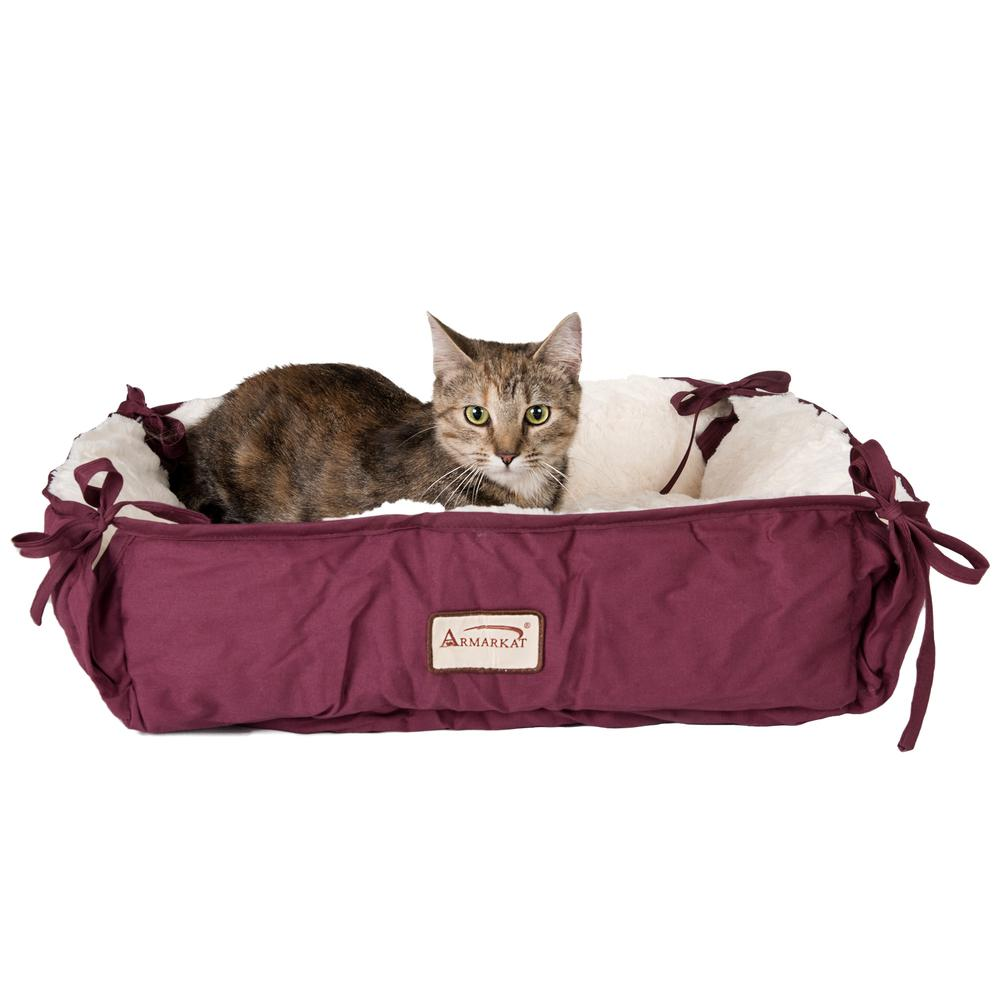 tabby cat laying down in plush burgundy cat bed