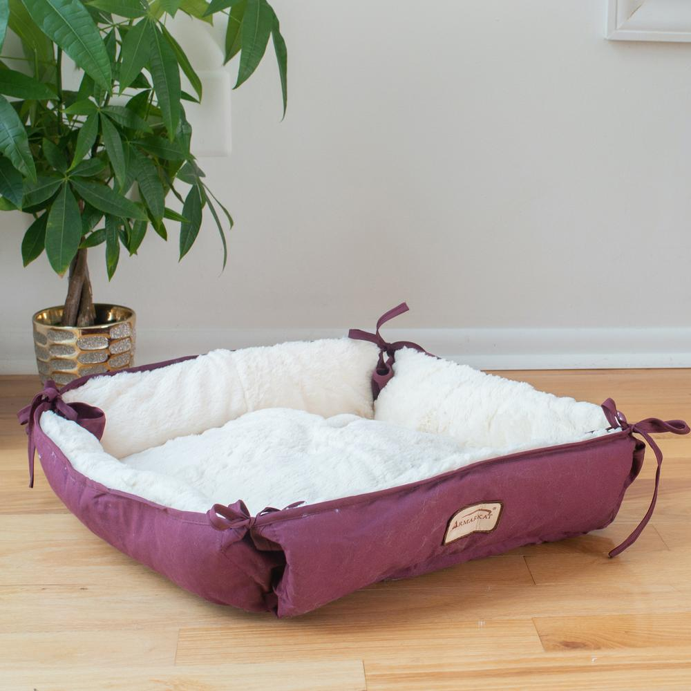 plush burgundy cat bed with a plant in a pot behind it