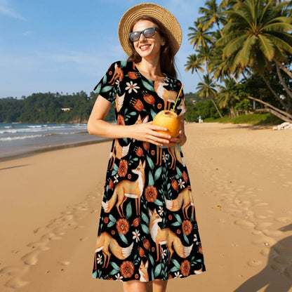 Black women's t-shirt dress featuring a floral and red fox pattern, perfect for a witchy vibe, on a beach background.